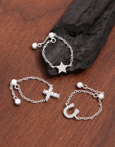 Close-up of adjustable silver chain rings with sparkling star and cross pendants