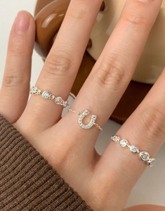 Close-up of S925 sterling silver horseshoe ring and pave cubic zirconia bands on fingers