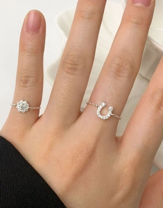 Detail of adjustable S925 sterling silver chain rings with pavé heart and flower charms