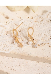 Detailed shot of golden twist earrings with white pearl and sparkling zircon accent