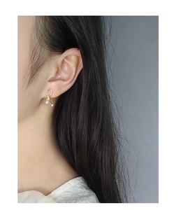 Side view of model wearing a gold ribbon bow earring with pearl and zircon detail