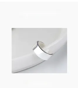 Close-up of a minimalist silver U-shaped ear cuff hanging on a white ceramic bowl edge