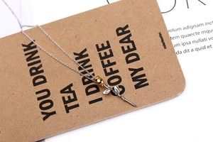 Detailed view of the gold and silver rose pendant necklace on a craft paper card