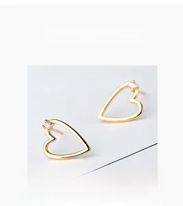 Close-up of heart-shaped gold stud earrings with sparkling round cubic zirconia stones