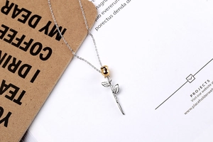Detail of a 3D gold rose pendant with silver stem on a minimalist necklace