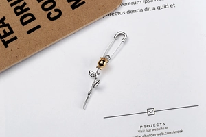 Macro detail of rose safety pin earring in dual-tone silver and gold plating