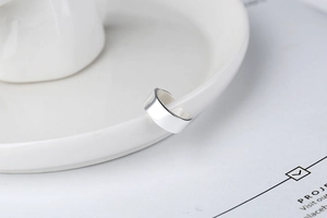 Close-up of polished S925 sterling silver U-shaped ear cuff on white ceramic tray