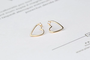 Close-up of minimalist gold heart stud earrings with sparkling cubic zirconia inlay