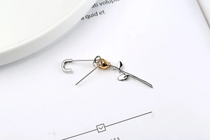 Detailed macro of S925 silver safety pin earring with a delicate golden rose bud flower