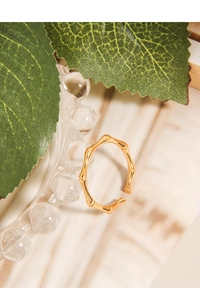 Détail de la bague ajustable en or à texture de bambou sur support en verre
