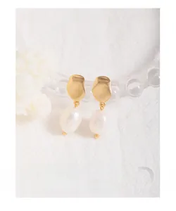 Detailed view of baroque pearl earrings with natural texture on a white fabric background