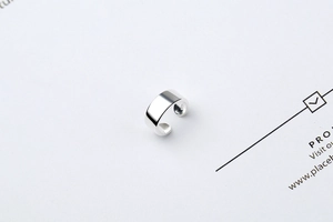Macro shot of minimalist S925 sterling silver ear cuff with polished finish and logo