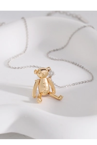 Détail d'un pendentif ours 3D doré avec des textures de couture sur céramique blanche
