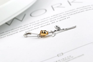 Close-up of two-tone rose flower brooch pin with silver leaves and golden metal bud