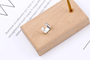 Detailed macro view of a minimalist S925 sterling silver U-shaped ear cuff on wooden block