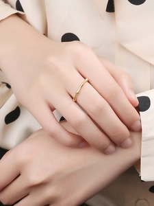Gros plan d'une bague en bambou doré minimaliste portée au doigt sous une lumière douce