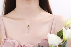 Detail of a 3D gold rose necklace with silver stem on an elegant female model