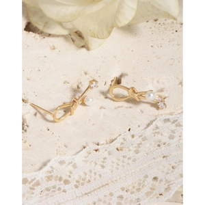 Elegant gold knot earrings featuring a white pearl and zircon on a stone surface
