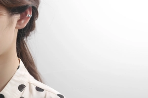 Close-up of a minimalist silver U-shaped ear cuff on the upper ear cartilage