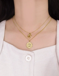 Détail d'un collier superposé en or avec portrait de reine et pendentif cœur sur modèle