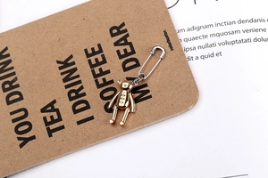 Détail d'une boucle d'oreille épingle de nourrice en argent avec pendentif ours doré