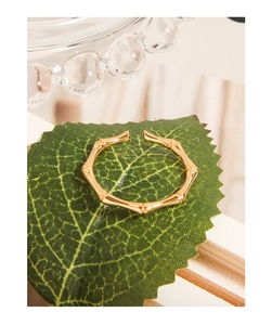 Gros plan d'une bague ouverte dorée style bambou avec structure articulée élégante