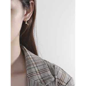 Elegant gold bow earrings with pearl and zircon detail shown on a model