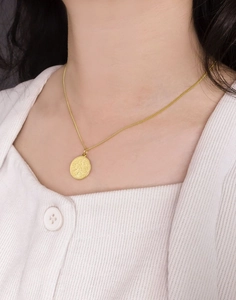 Gros plan d'un collier pendentif pièce en argent s925 vintage porté par un mannequin