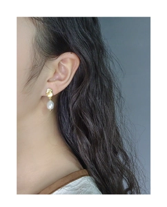 Macro view of S925 silver gold-plated earring with baroque pearl on female model