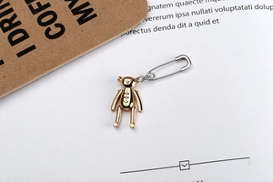 Détail d'un pendentif ours mécanique doré avec épingle de sûreté argentée sur magazine