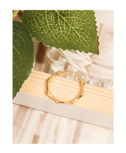 Détail d'une bague en argent doré au design bambou posée sur un socle en bois