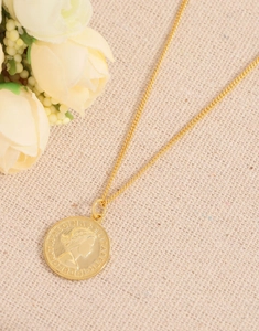 Vue détaillée du collier avec pièce en argent S925 doré et relief de reine sur lin