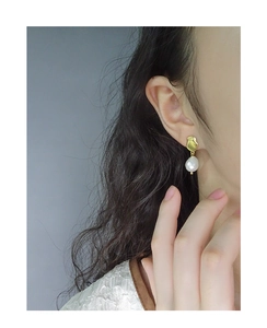 Close-up of S925 silver baroque pearl earrings on model's ear with golden metal base