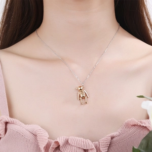 Pendentif ours en peluche doré avec chaîne en argent porté par un mannequin