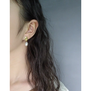 Baroque irregular pearl drop earrings in gold geometric design worn by a model