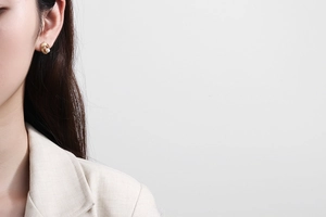 Detail of champagne gold spiral knot earrings with a lustrous pearl on female model