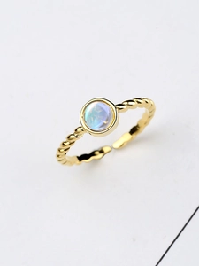 Detail of twisted gold band ring with a round luminous moonstone on white background