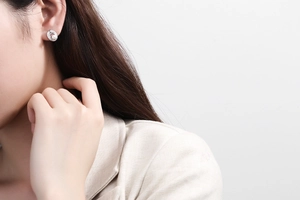 Detail showing elegant spiral silver earring with white pearl on model in white blazer
