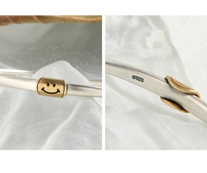 Macro detail of S925 sterling silver bangle featuring a golden smiley face charm