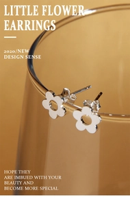 Macro view of minimalist S925 sterling silver hollow flower stud earrings on glass