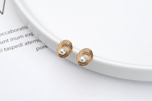 Close-up of spiral gold texture earrings with white pearl inlay for women