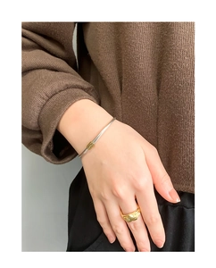 Detail of minimalist 925 sterling silver smile face bangle and textured gold ring