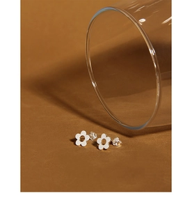 Macro shot of minimalist S925 sterling silver flower stud earrings on a brown surface
