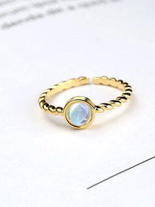 Macro shot of gold adjustable twisted rope ring featuring a glowing moonstone gem