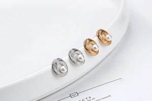 Detailed close-up of S925 silver spiral stud earrings with white pearls in gold and silver