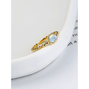 Macro detail of a moonstone gold ring with twisted rope band and adjustable open design