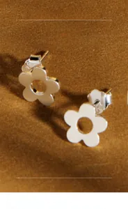 Macro shot of minimalist hollow flower stud earrings in polished sterling silver