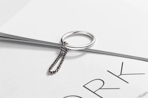 Primo piano di un anello minimalista in argento S925 con dettaglio catena pendente