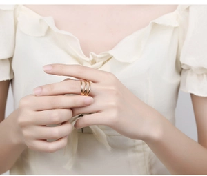 Detail shot of a minimalist triple-layer golden flowing ring worn on a finger