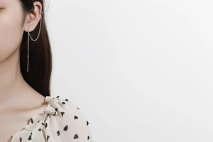 Detail of silver long tassel ear cuff and drop chain earrings on a female model